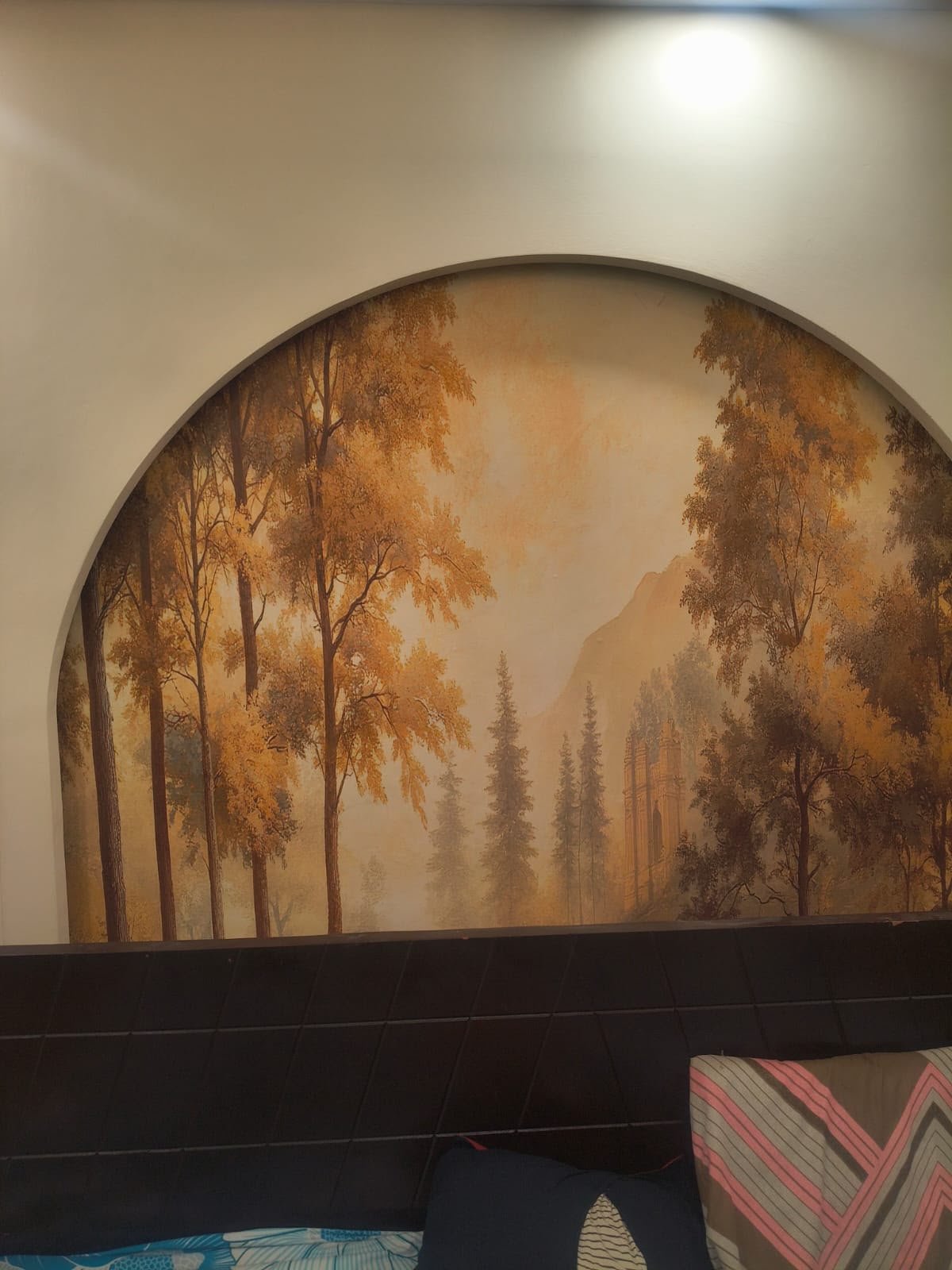 Arched forest mural above a bed headboard